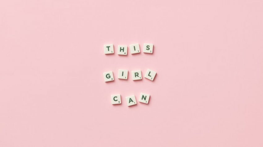 Scrabble tiles spelling 'This Girl Can' on a pink background.